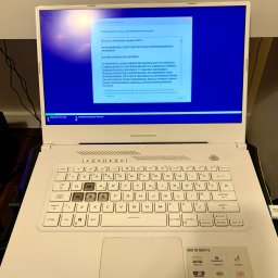 Leo Serwis Montaż i Demontaż - Laptop ASUS TUF Dash F15 z widocznym procesem instalacji systemu Windows na ekranie. Na obudowie naklejki z informacjami o specyfikacji, w tym Wi-Fi 6, Thunderbolt 4 oraz karta graficzna RTX.