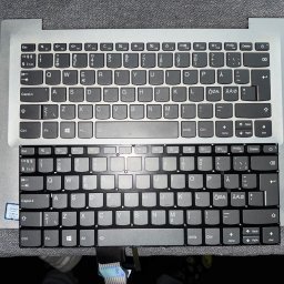 Leo Serwis Montaż i Demontaż - Porównanie nowej (górnej) i starej (dolnej) klawiatury laptopa Lenovo, z widocznym złączem taśmowym, gotowych do wymiany na szarym tle.