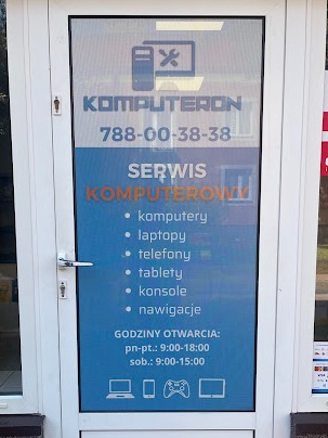 Reklama serwisu komputerowego naklejona na szklanych drzwiach wejściowych, z listą urządzeń objętych usługą, numerem telefonu i godzinami otwarcia.