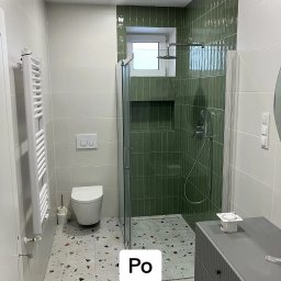 Renovation&You - Wykończona łazienka z zielonymi płytkami w kabinie prysznicowej, jasnymi płytkami na ścianach, toaletą wiszącą i grzejnikiem drabinkowym, podłoga wyłożona płytkami imitującymi lastryko.