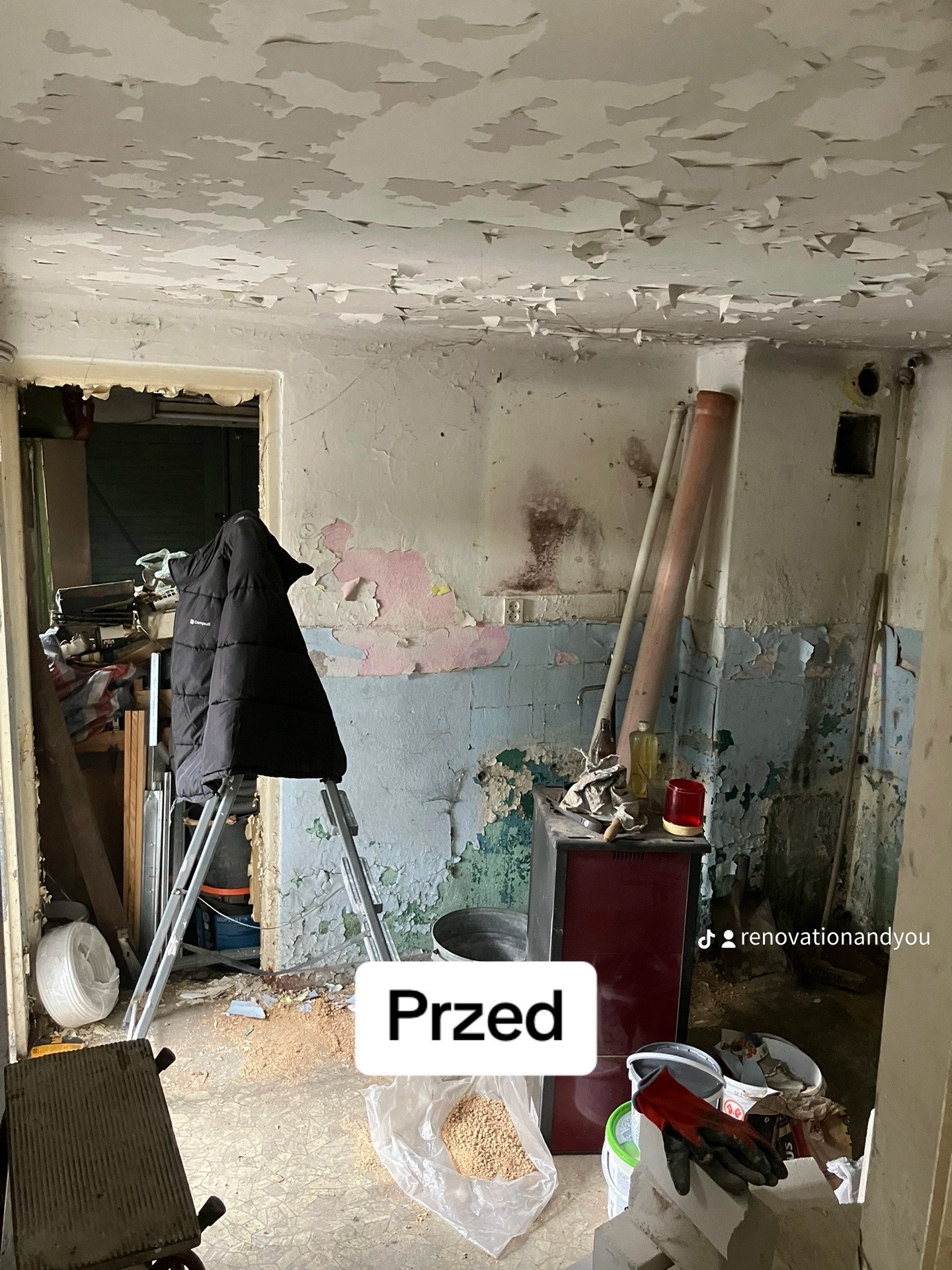 Pokój przed remontem: odpadająca farba na ścianach i suficie, drabina z kurtką, piec, gruz i narzędzia na podłodze.