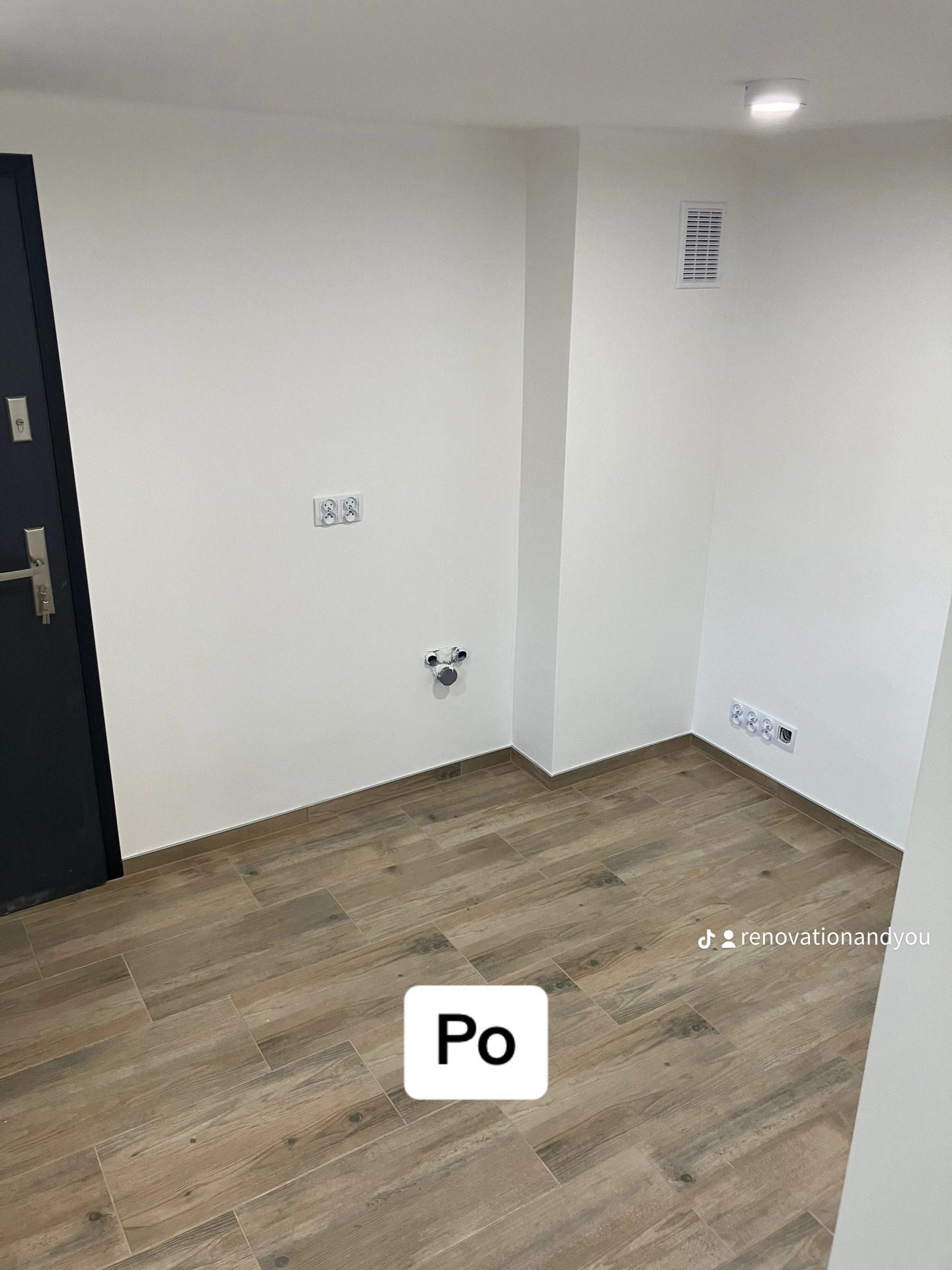 Puste pomieszczenie po remoncie, z nową drewnopodobną podłogą z płytek, świeżo pomalowanymi białymi ścianami, gniazdkami elektrycznymi i kratką wentylacyjną.