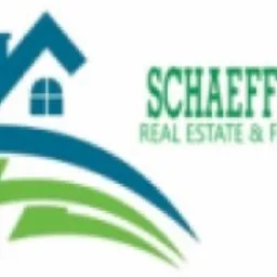 Logo firmy Schaeffler Real Estate & Finance z motywem domu w kolorach niebieskim i zielonym, stylizowane fale pod budynkiem.