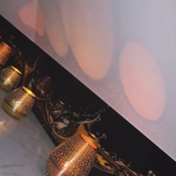 Studio Szkła Rzeszów - Dekoracyjny panel szklany z motywem rozbryzgującej się cieczy, oświetlony od wewnątrz ażurowymi lampionami, tworząc ciepłą, refleksyjną atmosferę.