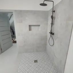 Wykończona kabina prysznicowa z deszczownicą i wzorzystą posadzką w odcieniach szarości, w łazience po remoncie w Białymstoku. W tle widoczne otwarte drzwi.