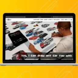 Laptop wyświetla stronę internetową z formularzem zamówień na odręczne rysunki samochodów. Na ekranie widoczny mężczyzna rysujący samochód, obok rozłożone szkice aut i zestaw markerów.
