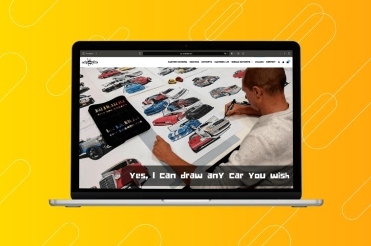 Laptop wyświetla stronę internetową z formularzem zamówień na odręczne rysunki samochodów. Na ekranie widoczny mężczyzna rysujący samochód, obok rozłożone szkice aut i zestaw markerów.