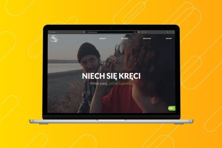 Laptop wyświetla stronę internetową z hasłem 'NIECH SIĘ KRĘCI' i zdjęciem trzech osób, umieszczony na żółtym tle z białymi liniami.