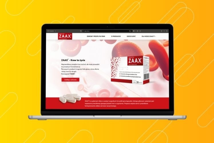 Laptop wyświetla stronę internetową suplementu diety ZAAX z czerwonym motywem przewodnim, prezentującą opakowanie produktu, kapsułki i hasło 'ZAAX - Krew to życie'.