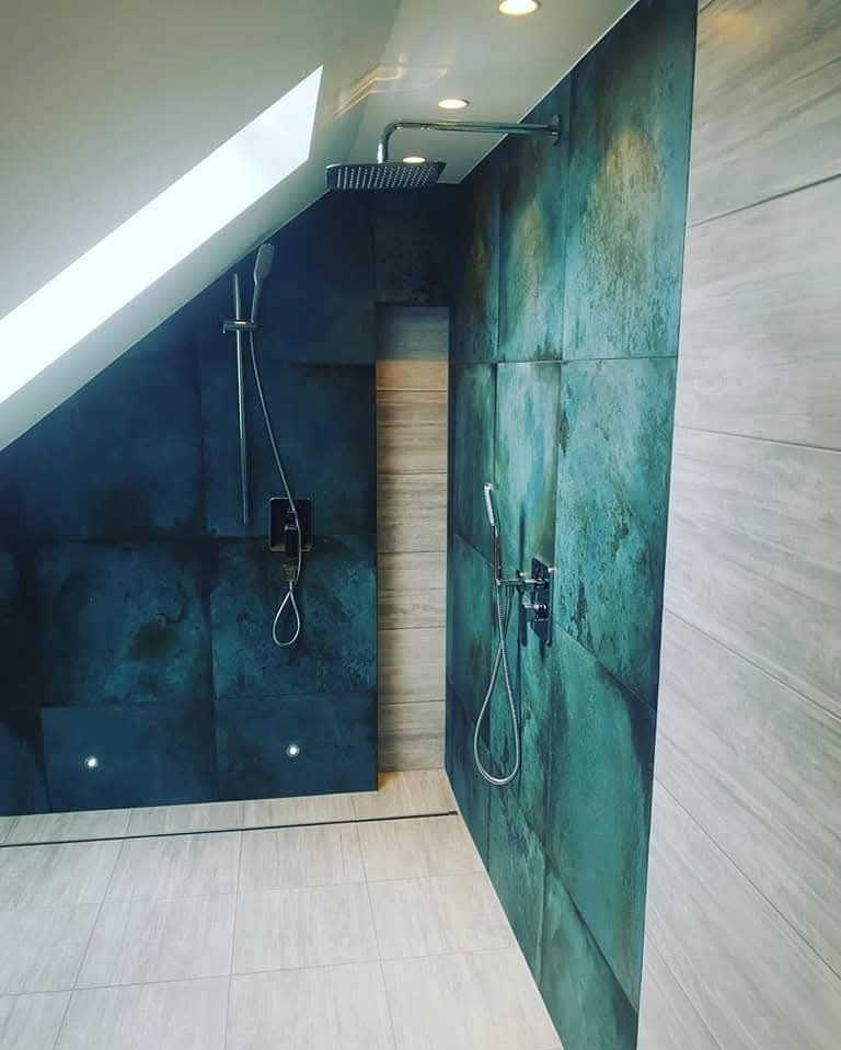 Nowoczesna łazienka na poddaszu z kabiną prysznicową wyłożoną dużymi, turkusowymi płytami o nieregularnej fakturze, z chromowaną armaturą i punktowym oświetleniem.