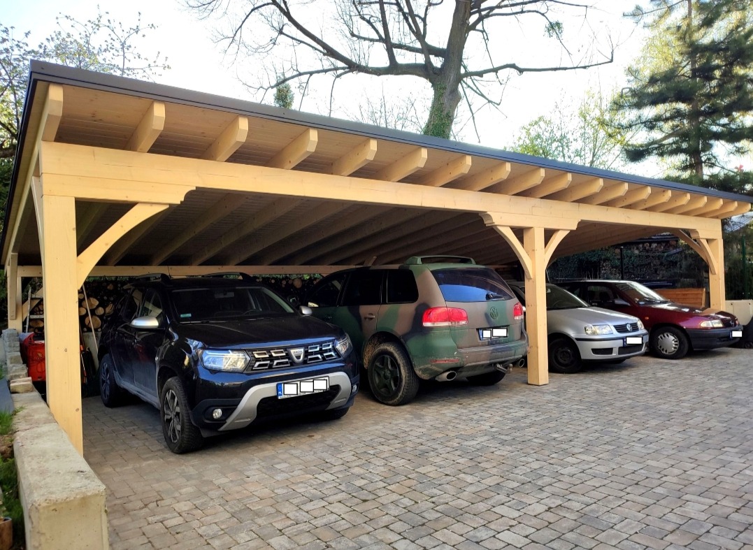 Drewniana wiata garażowa z czterema samochodami w Tarnowie, widok z zewnątrz na kostkę brukową.