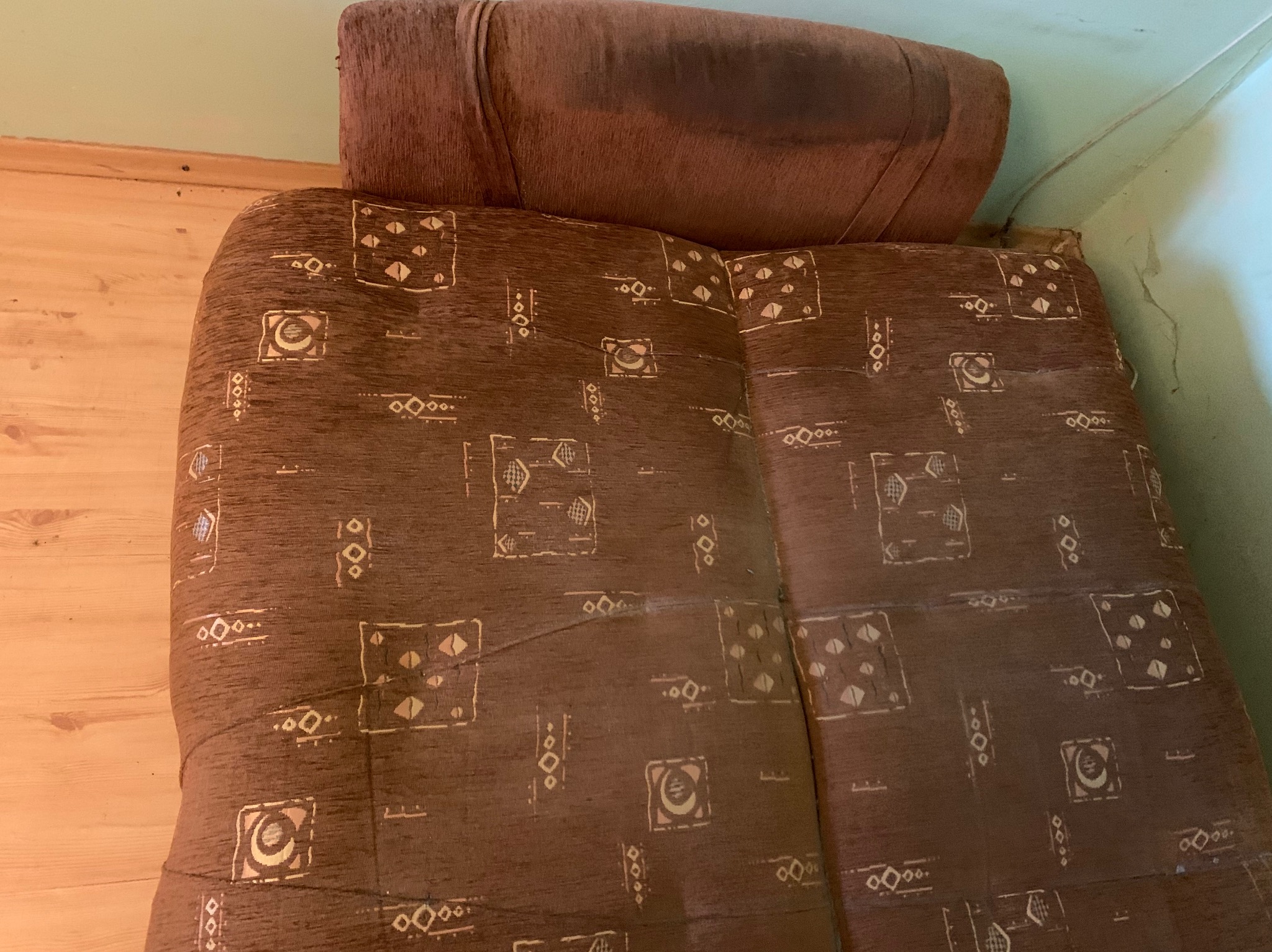 Brązowa kanapa z wzorzystą tapicerką, widoczne ślady użytkowania i zabrudzenia, sfotografowana w Białymstoku.