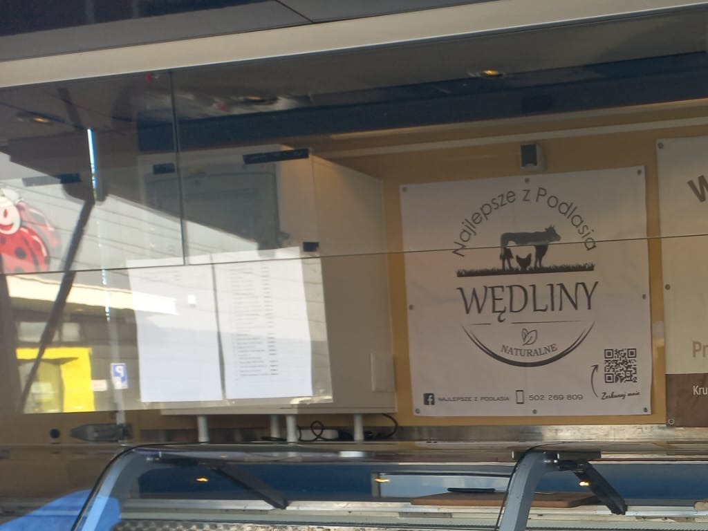 Okleina food trucka z logotypem 'Najlepsze z Podlasia', prezentująca wędliny naturalne. Widoczny numer telefonu i kod QR. Ujęcie z perspektywy klienta.
