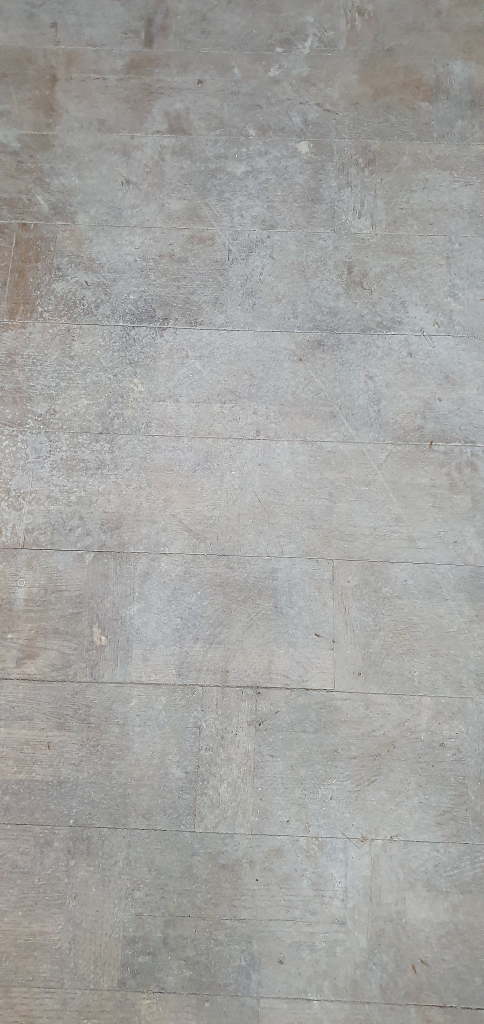 Szare deski podłogowe z widocznymi śladami użytkowania i zarysowaniami, ukazujące potrzebę renowacji. Widok z góry na parkiet przed cyklinowaniem.