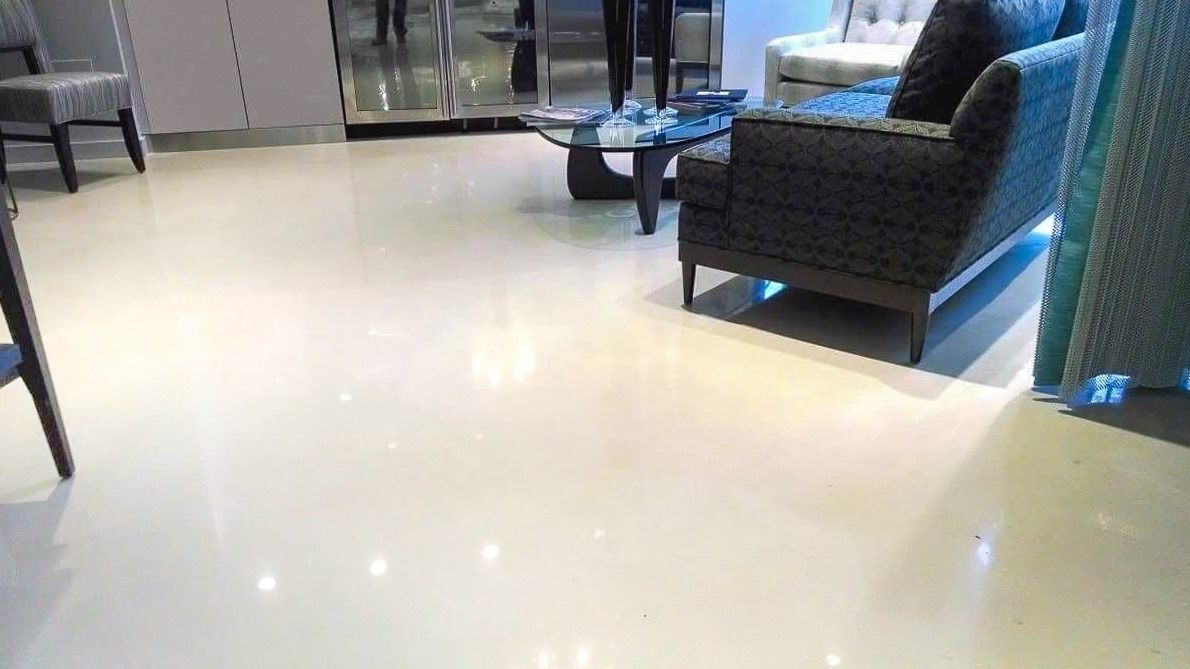 Błyszcząca, kremowa posadzka w salonie z meblami w tle, odbijająca światło, podkreślona delikatnym oświetleniem pod sofą.