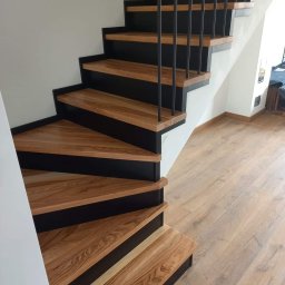 Kuchnie szafy Kita - Drewniane schody spiralne z czarnymi podstopnicami i metalową balustradą, widoczne z dołu, z parkietem na podłodze.