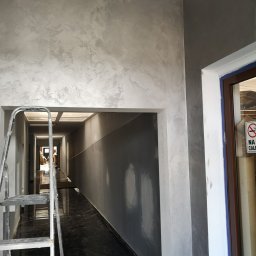 Daniel Nowik - Korytarz po nałożeniu dekoracyjnej, srebrzystej farby na ścianach, widoczna drabina i wiadro z wałkiem malarskim, marmurowa podłoga.