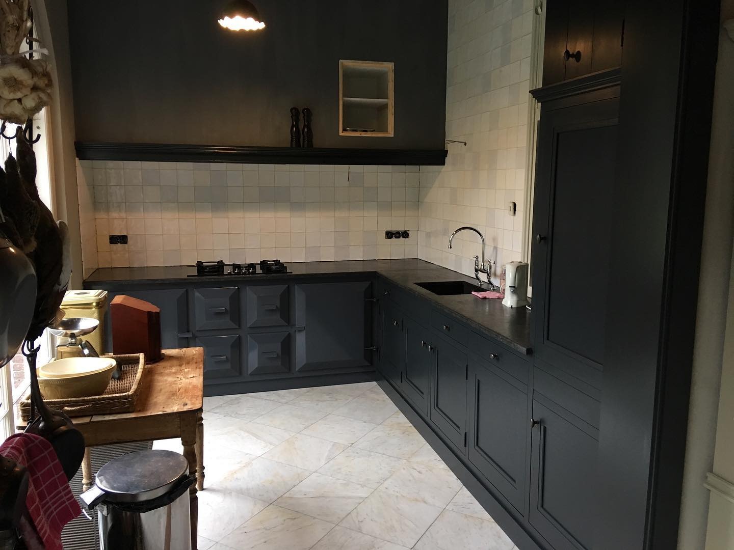 Ciemna kuchnia na wymiar w Chwałkowie Kościelnym z frezowanymi frontami i blatem z ciemnego kamienia, widok na płytki ścienne i marmurową podłogę.