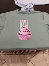 Jasnozielona koszulka z nadrukiem babeczki z różowym kremem i napisem 'SPOKO BAKE CAFE' w pionowych liniach.