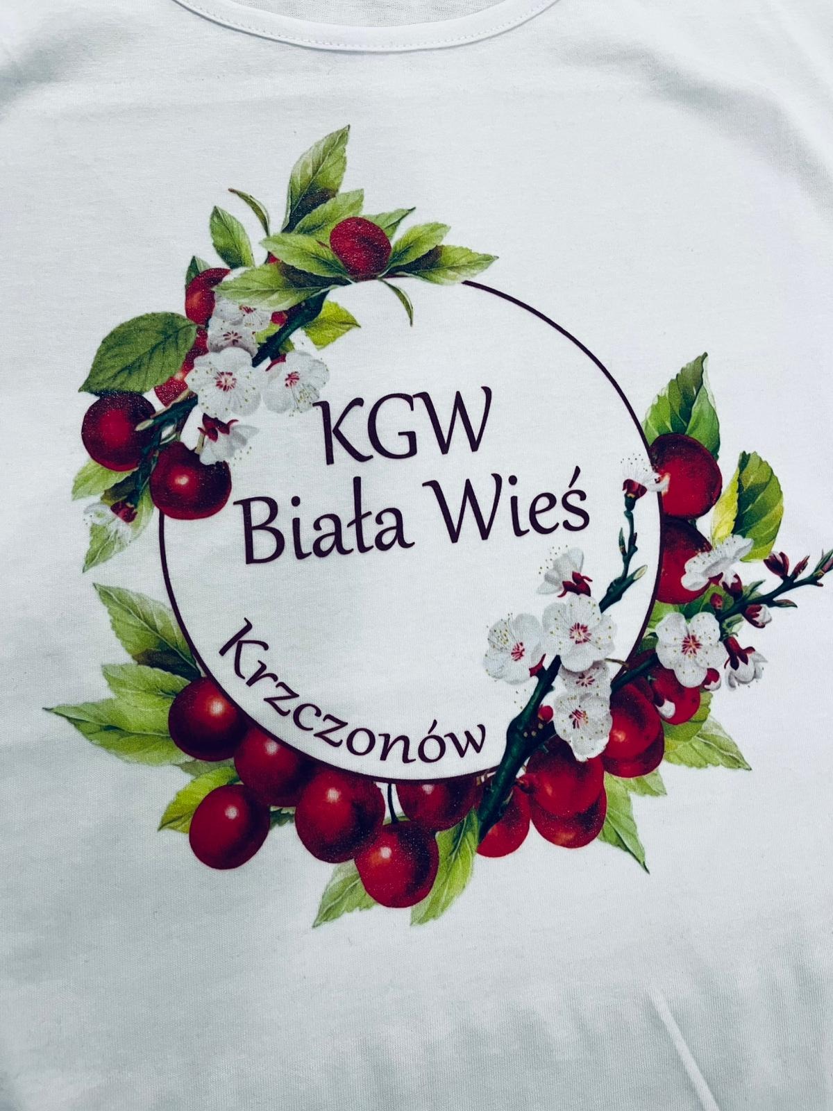 Biała koszulka z nadrukiem wieńca z wiśni, kwiatów i napisem 'KGW Biała Wieś Krzczonów'.