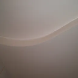 Fragment sufitu z dekoracyjnym, falistym elementem gipsowym, widoczne łączenie płyt kartonowo-gipsowych.