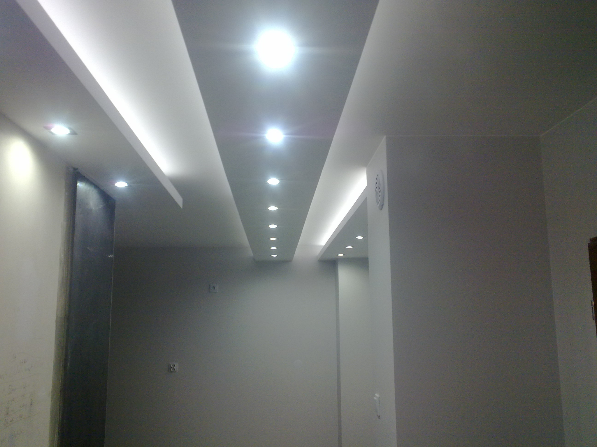 Oświetlenie sufitowe z płyt kartonowo-gipsowych z wbudowanymi punktami świetlnymi w nowocześnie wykończonym wnętrzu.