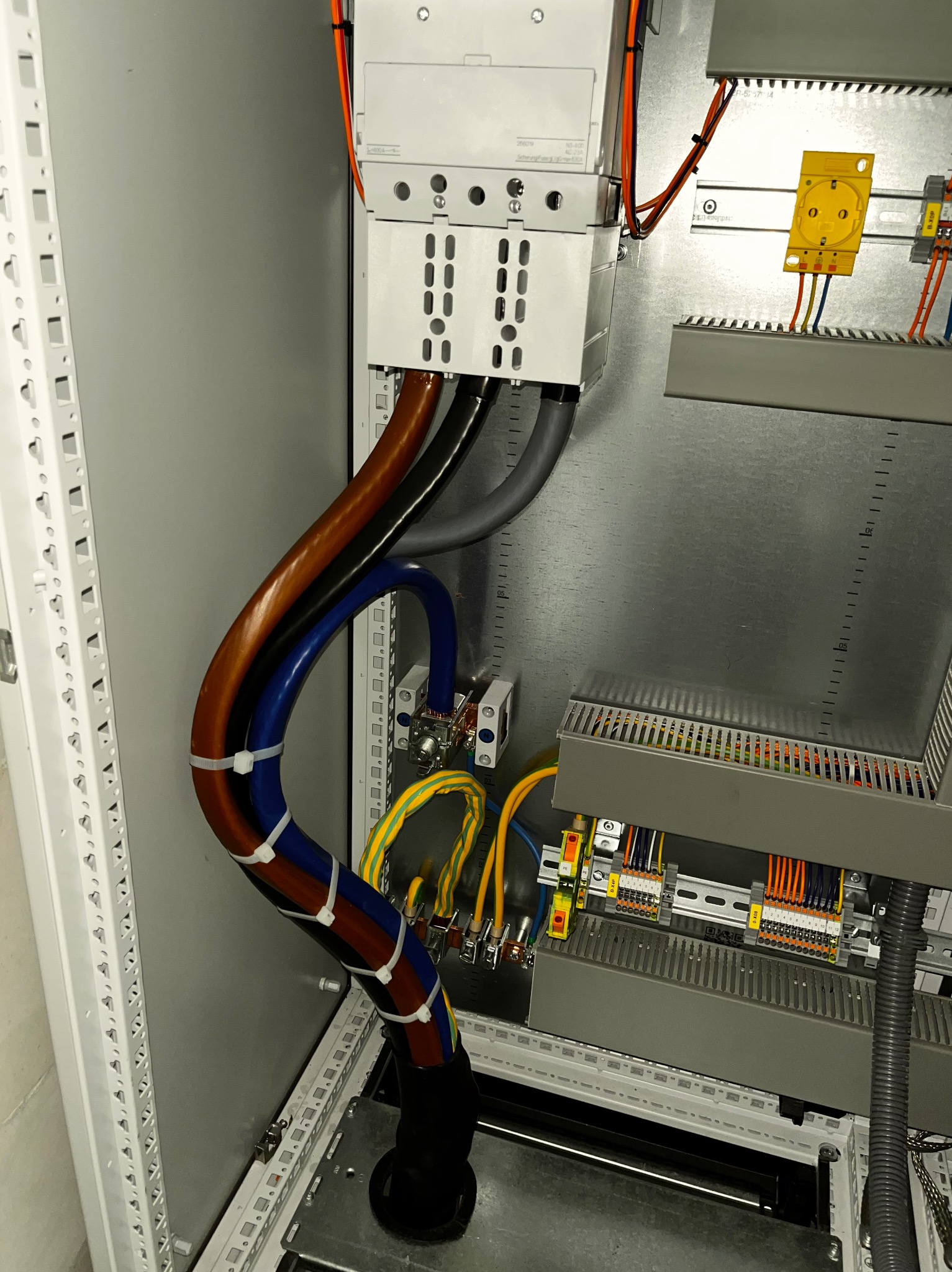 Wnętrze szafy sterowniczej z uporządkowanymi przewodami o różnych kolorach, zabezpieczonymi opaskami zaciskowymi i podłączonymi do listew zaciskowych.