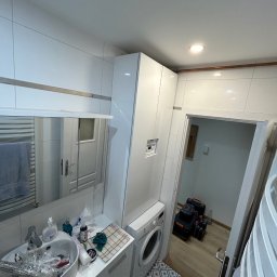 NaVo-Bud - Łazienka w trakcie prac wykończeniowych: widoczna pralka, umywalka z akcesoriami, płytki podłogowe z wzorem geometrycznym oraz skrzynki narzędziowe w przyległym pomieszczeniu.