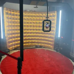 Złota, dmuchana ścianka tła z oświetleniem LED i czerwonym dywanem w przestrzeni do robienia zdjęć, z widocznymi bąbelkami unoszącymi się w powietrzu.