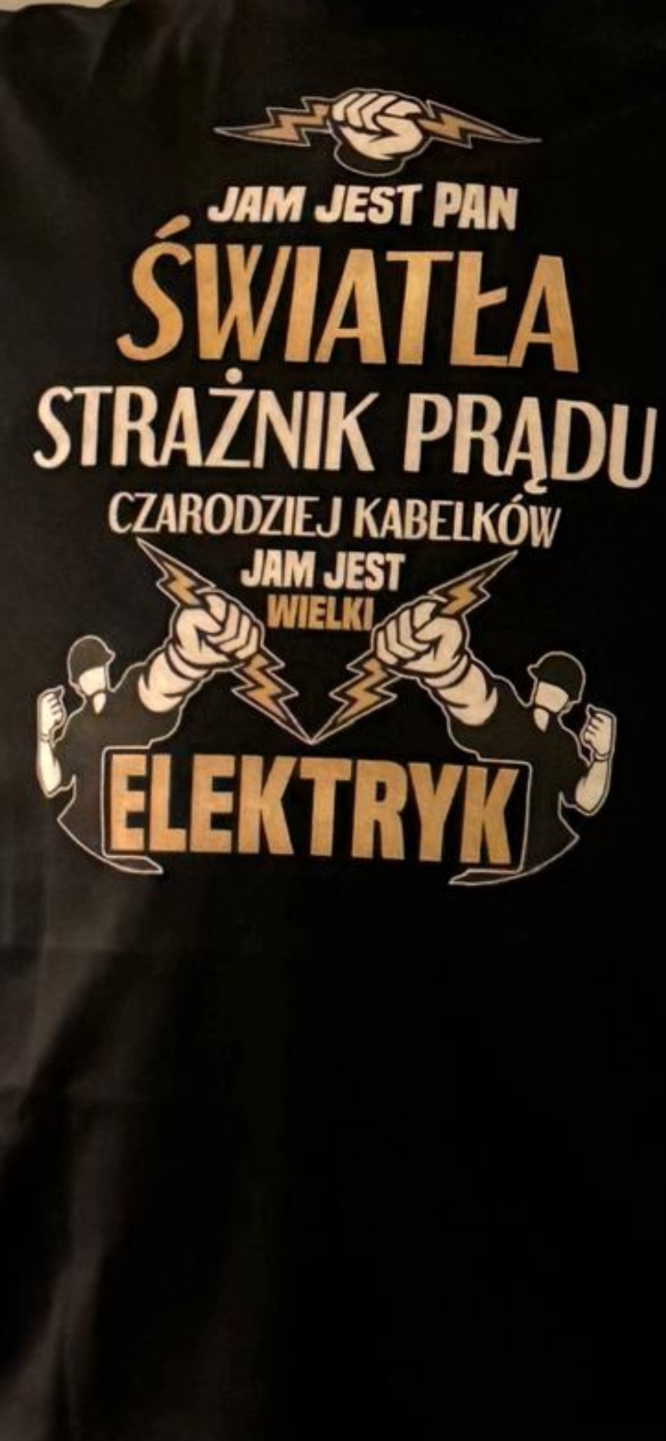 Czarna koszulka z nadrukiem w kolorze złotym, przedstawiającym stylizowany napis 'JAM JEST PAN ŚWIATŁA STRAŻNIK PRĄDU CZARODZIEJ KABELKÓW JAM JEST WIELKI ELEKTRYK' oraz grafiki dwóch postaci...