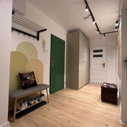 MLT IT Paweł Góral - Nowoczesny przedpokój z drewnianą podłogą, zielonymi drzwiami, szarą szafą, oświetleniem punktowym na suficie, wieszakiem na ścianie, ławką z poduszką i półką na buty.