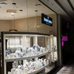 Witryna sklepowa z biżuterią, prezentująca naszyjniki, kolczyki i bransoletki na białych ekspozytorach. Nad witryną widoczny szyld 'ŚWIAT ZŁOTA'.