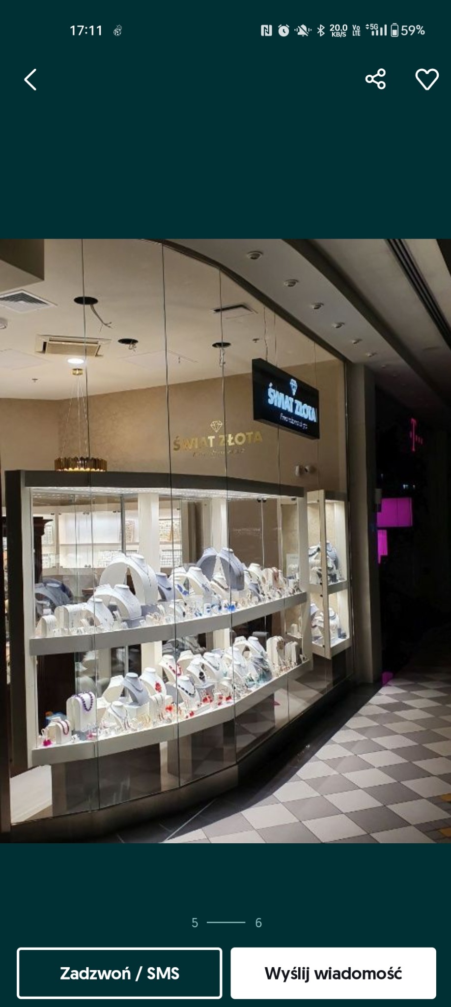 Witryna sklepowa z biżuterią, prezentująca naszyjniki, kolczyki i bransoletki na białych ekspozytorach. Nad witryną widoczny szyld 'ŚWIAT ZŁOTA'.