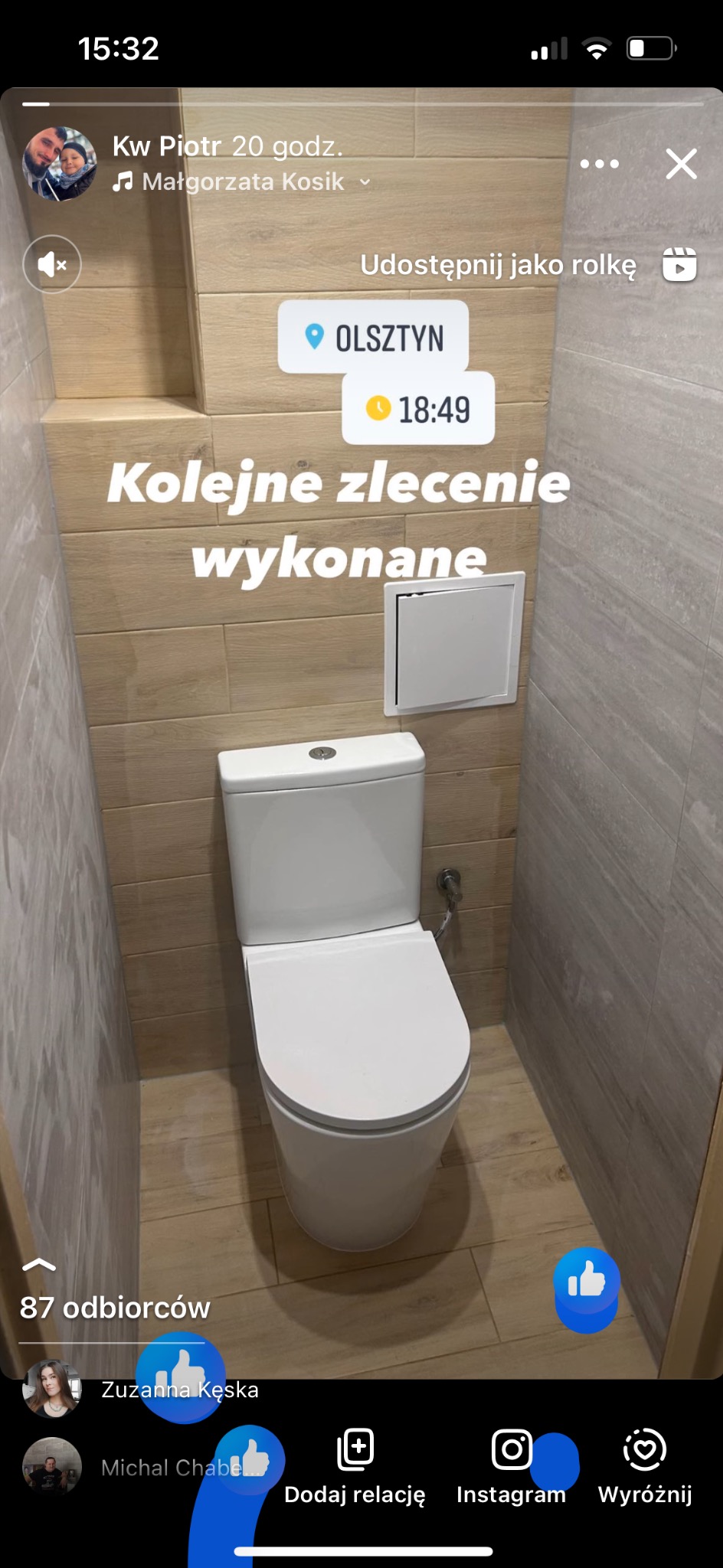Biała toaleta kompaktowa w wykończonej łazience, widoczna klapka rewizyjna, ściany wyłożone płytkami imitującymi drewno i szary kamień.