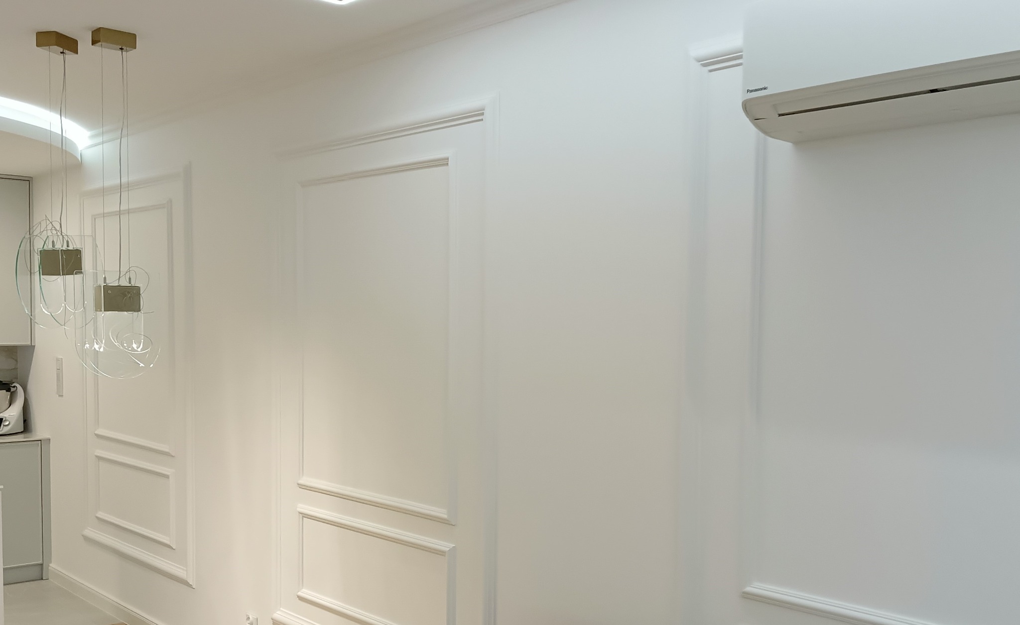 Jasne wnętrze z dekoracyjnymi panelami ściennymi, nowoczesną lampą wiszącą i klimatyzatorem Panasonic.