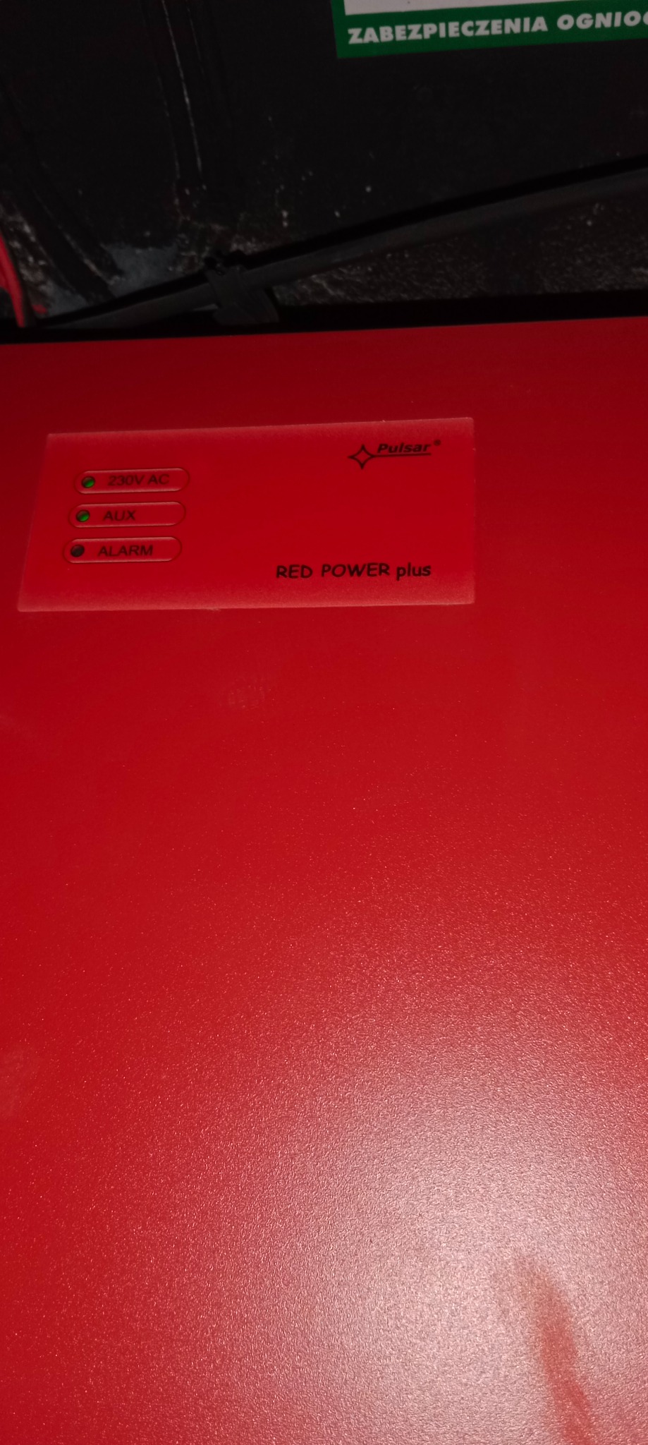 Czerwona obudowa centrali alarmowej Pulsar Red Power Plus z trzema zielonymi diodami sygnalizacyjnymi: 230V AC, AUX i ALARM.