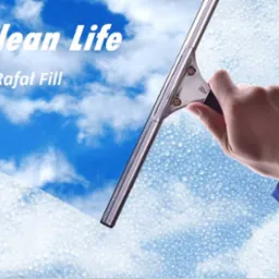 Ręka w niebieskiej koszuli czyści okno za pomocą ściągaczki, za oknem widoczne błękitne niebo z chmurami.