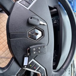 FHU EXITO Fita Arkadiusz - Czarna kierownica Renault z dwoma kluczykami, jeden z pilotem i brelokiem z napisem EWI M7Q4, leżącymi na centralnej części z logo.