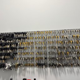 FHU EXITO Fita Arkadiusz - Ściana warsztatu ślusarskiego z ekspozycją różnorodnych kluczy, w tym kluczy samochodowych z pilotami, zawieszonych na perforowanej płycie.