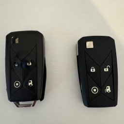 FHU EXITO Fita Arkadiusz - Dwa czarne kluczyki samochodowe z gumowymi przyciskami na jasnym tle. Jeden kluczyk jest rozłożony, ukazując metalowy grot.