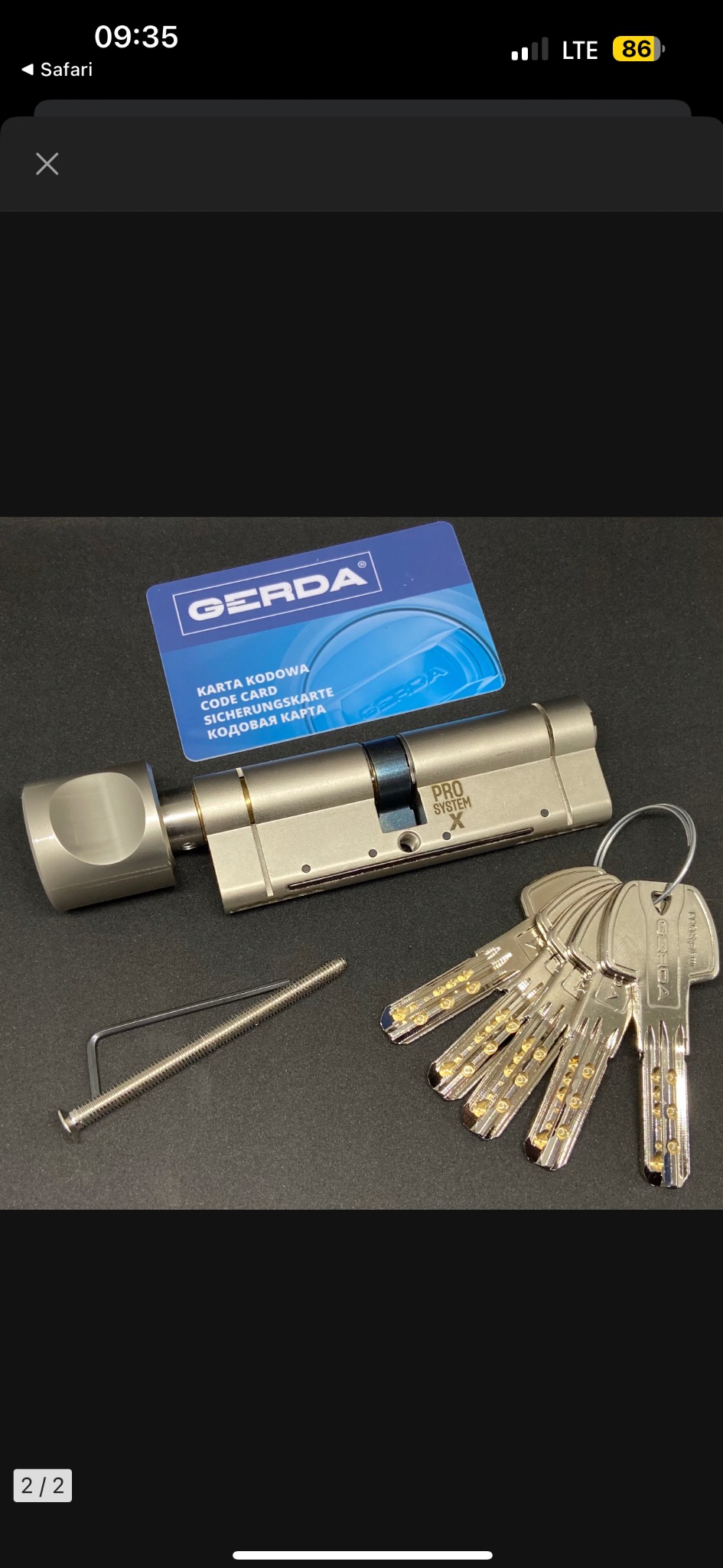 Nowy, srebrny zamek Gerda Pro System X z kompletem kluczy, śrubą montażową i kartą kodową na czarnym tle.