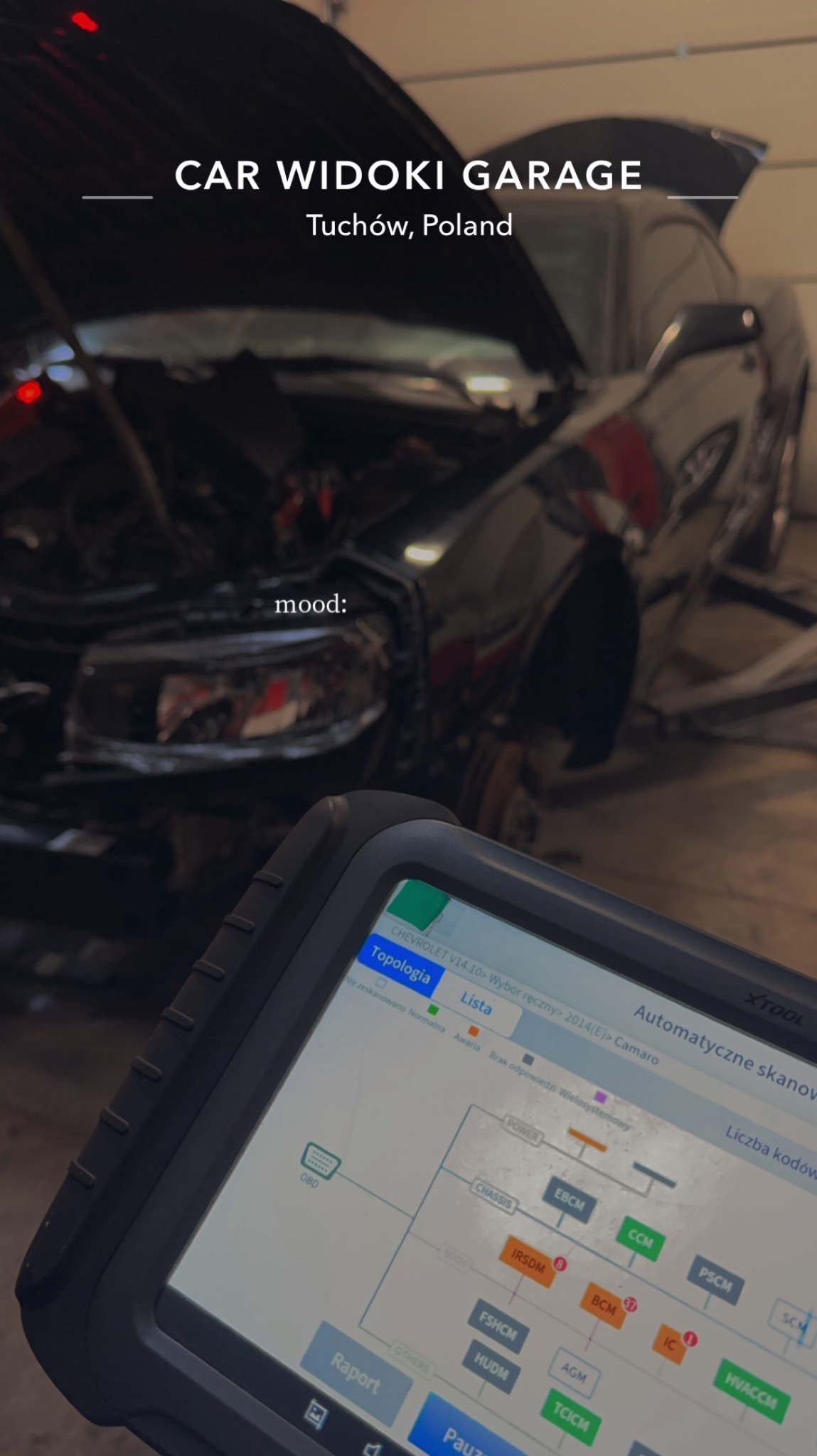 Czarny samochód z otwartą maską w warsztacie, w tle narzędzia, na pierwszym planie tablet diagnostyczny z widocznym schematem połączeń elektronicznych Chevrolet Camaro.