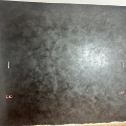 Denys Karpovych - Ściana pomalowana na ciemny, metaliczny kolor z widoczną fakturą. Widoczne puszki elektryczne i fragment podłogi z płytek.