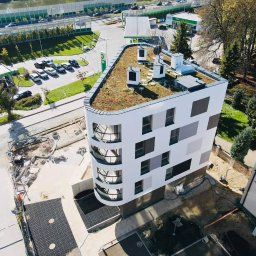 GRUPA POMORSKA PERłA SP. Z O.O. - Widok z góry na nowoczesny budynek z zielonym dachem w pobliżu stacji benzynowej BP, z placem budowy w tle.