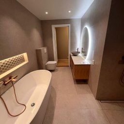 Artur Hinc - Nowoczesna łazienka z wolnostojącą wanną, umywalką nablatową z podświetlanym lustrem i heksagonalnymi płytkami w niszy ściennej.