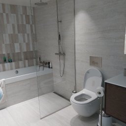 Artur Hinc - Jasna łazienka w Wielkim Gowinie z kabiną prysznicową typu walk-in, wiszącą toaletą i umywalką z szafką w odcieniach brązu, wykończona płytkami imitującymi marmur.