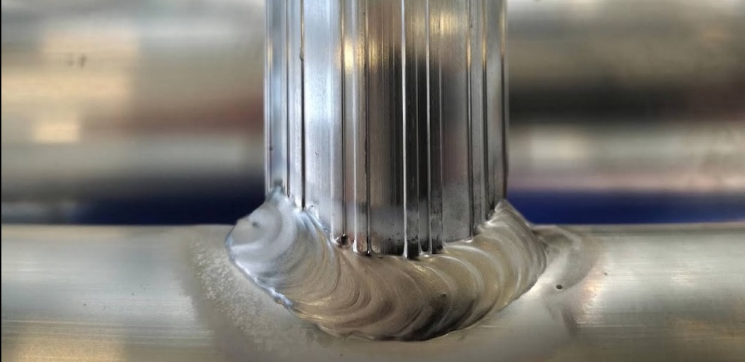 Spoina łącząca profil z rurą, widoczne ślady obróbki i charakterystyczny wzór po procesie łączenia metali.