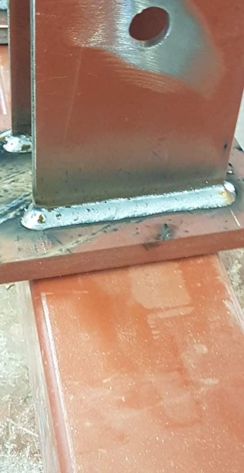 Połączenie spawane dwóch elementów konstrukcyjnych ze stali, widoczne ślady spawania i otwór w jednym z elementów.