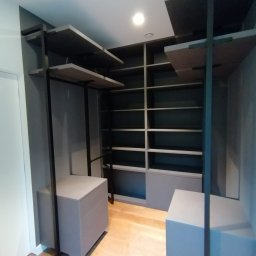 AKKER MEBLE Yurii Pakenas - Nowoczesna garderoba z otwartymi półkami i szufladami w odcieniach szarości, z drewnianą podłogą, minimalistyczny design.