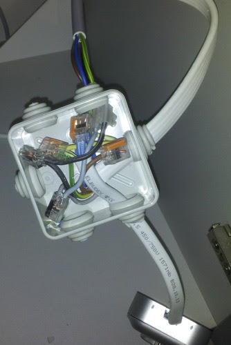 Otwarta puszka elektryczna z widocznymi przewodami w różnych kolorach i złączkami WAGO, zamontowana na suficie, z podłączonymi kablami Elbudex 450/750V.